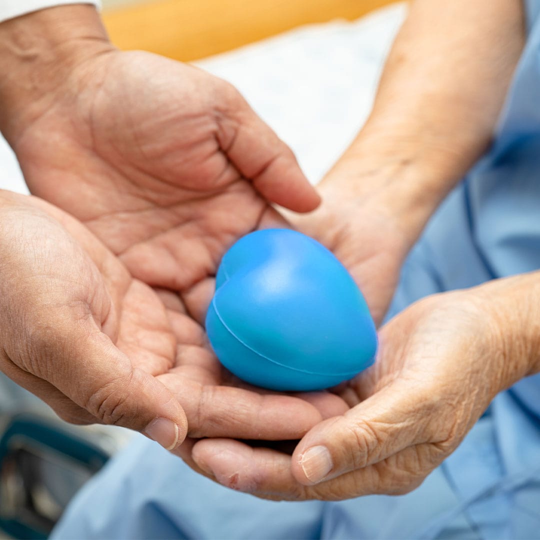 Un médecin donne un coeur bleu à une patiente âgée dans sa main sur un lit d'hôpital.